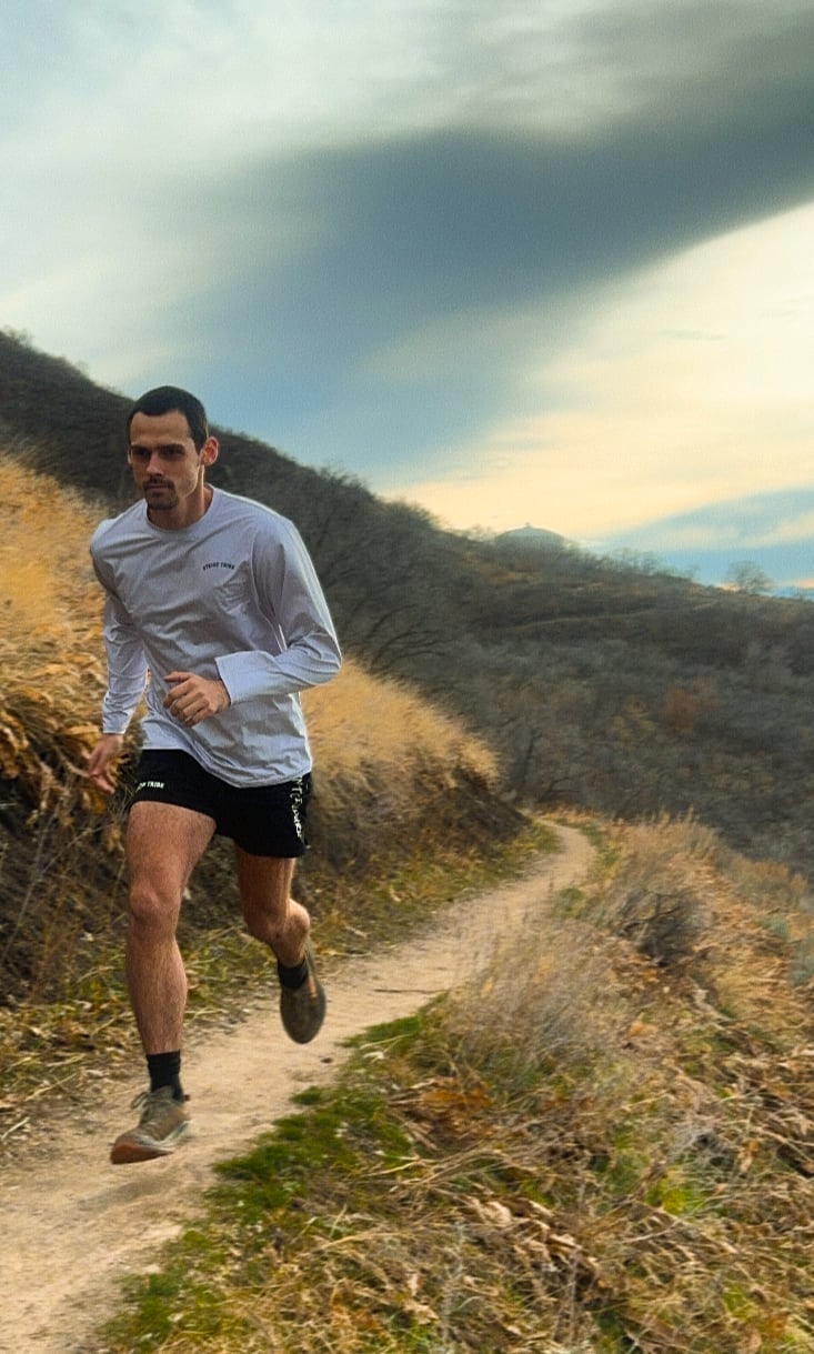 Man running on a trail with a mountainous landscape in the background