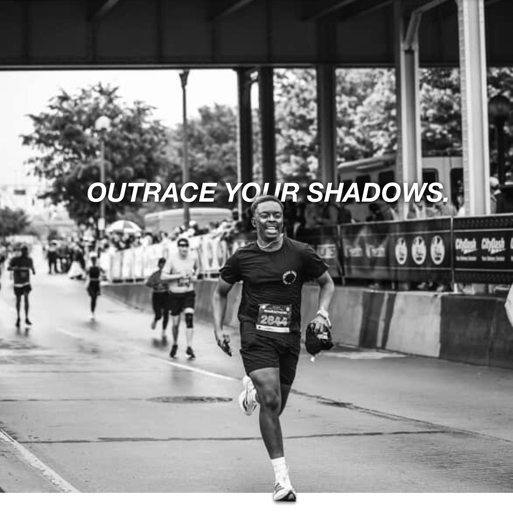 Black and white photo of a runner with 'Outrace Your Shadows' text at a race event.